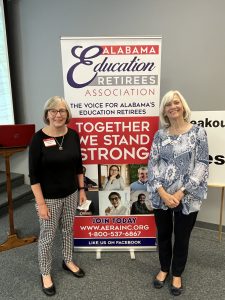 Two women standing on either side of a banner reading Alabama Education Retirees Association, Together We Stand Strong.